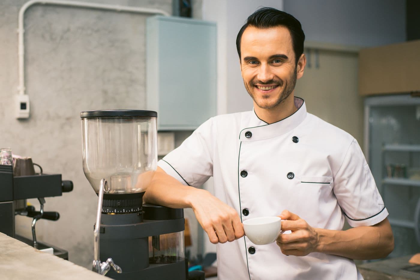 A cafe owner behind the counter holding a fresh coffee